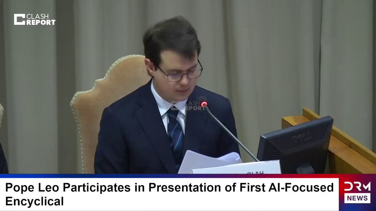 바티칸 회의실에서 종이를 읽는 Chris Olah — 안경, 흰 셔츠, 짙은 정장. 화면 하단 자막 'Pope Leo Participates in Presentation of First AI-Focused Encyclical'
